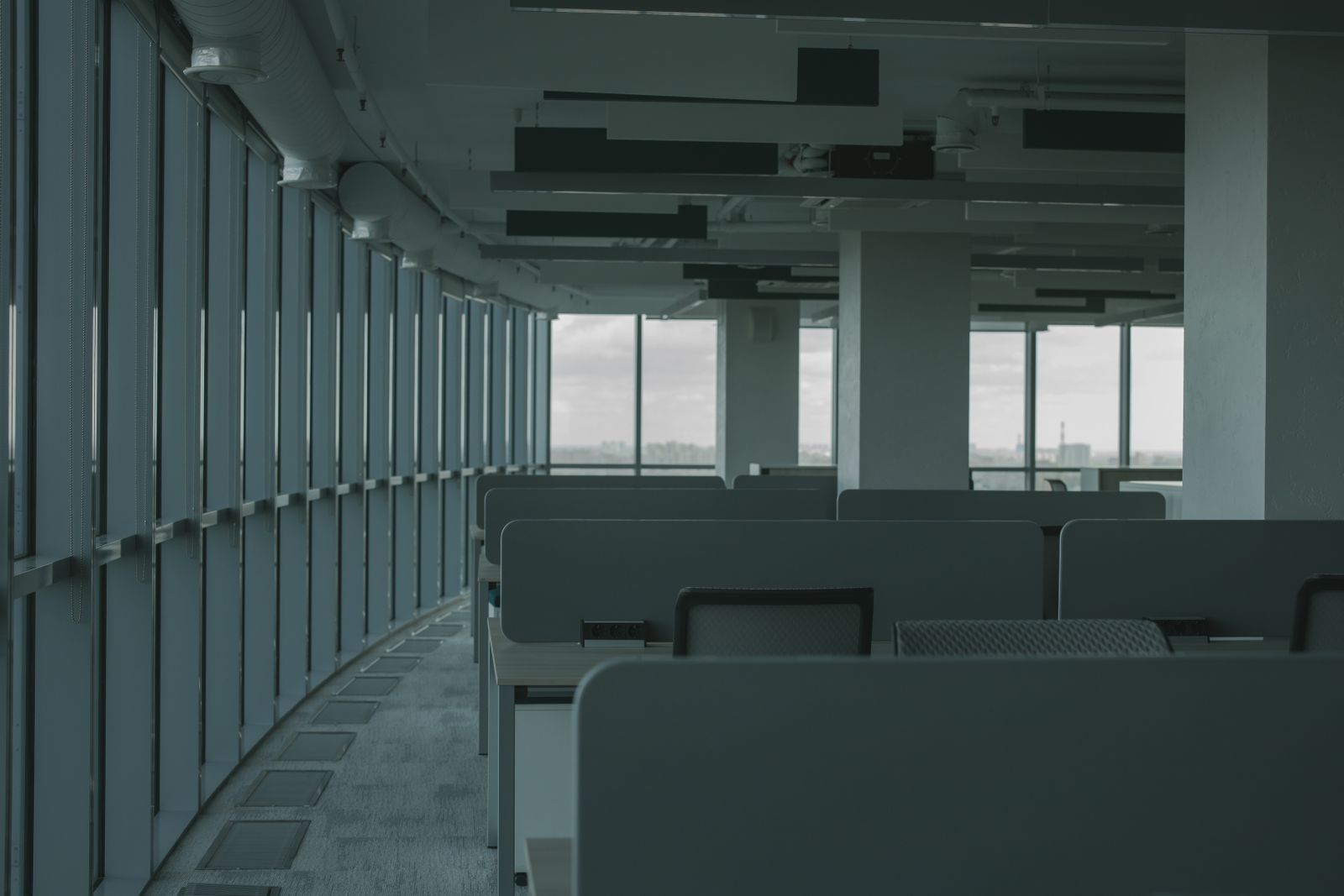 Cam cepheli, düzenli ve boş bir kurumsal ofis alanı, sıra sıra çalışma masalarıyla